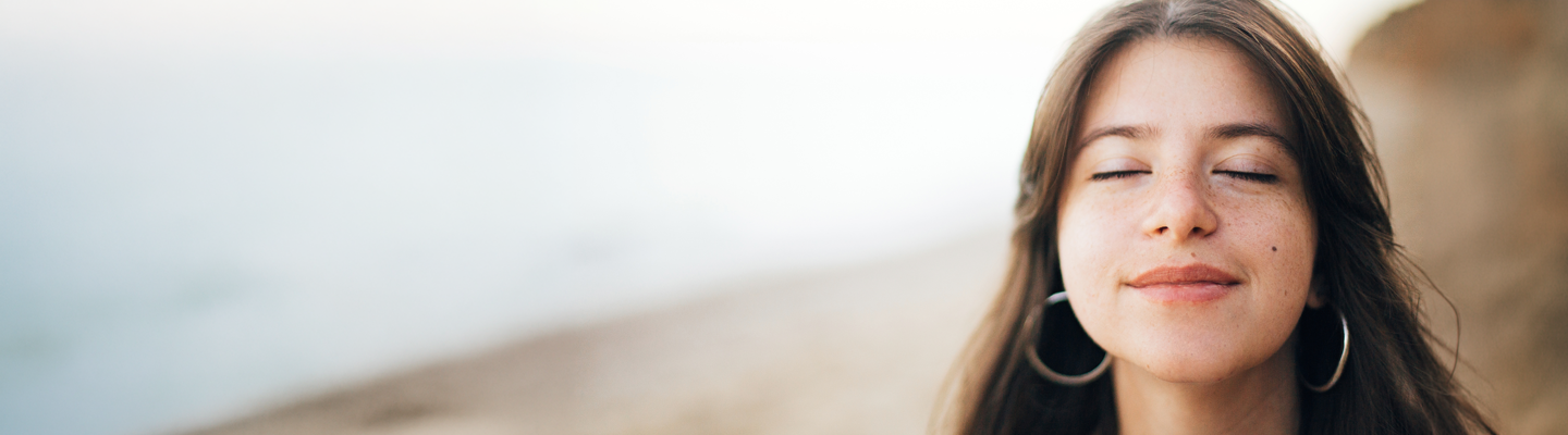 Femme sereine, les yeux fermés, au bord de la mer